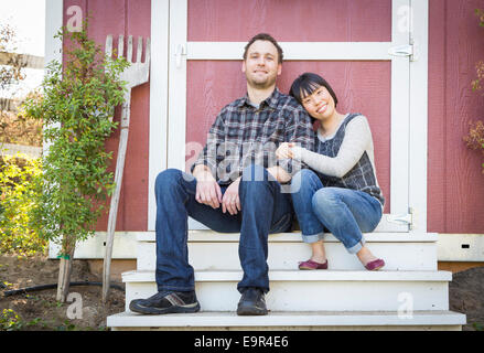 Happy Mixed Race Couple Relaxing on the Steps of Their Barn. Stock Photo