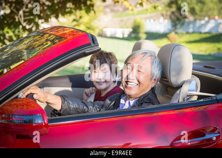 Attractive Happy Chinese Couple Enjoying An Afternoon Drive in Their Convertible. Stock Photo