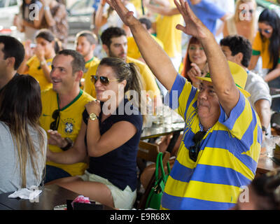 Cheerful Brazil fans watching World Cup football match on TV at a bar in Salvador, Bahia, Brazil. Stock Photo