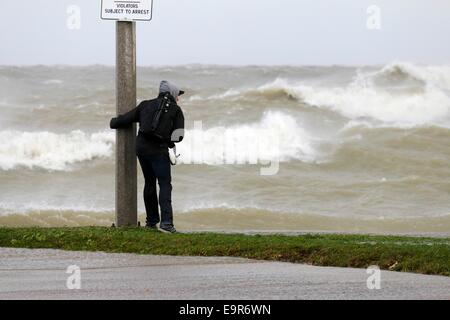 Chicago, Illinois, USA. 31st October, 2014. A photographer steadies himself against the wind at the Chicago lakefront. Gale force winds produced waves of over 20 feet as measured at a NOAA weather buoy far out on Lake Michigan. Credit:  Todd Bannor/Alamy Live News