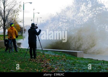 Chicago, Illinois, USA. 31st October, 2014. A photographer risks a soaking as a large Lake Michigan wave crashes ashore during today's gale. Gale force winds produced waves of over 20 feet as measured at a NOAA weather buoy far out on the big lake. Credit:  Todd Bannor/Alamy Live News