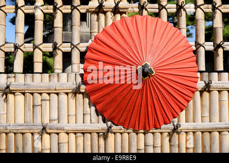 Japanese traditional red umbrella with bamboo fence Stock Photo