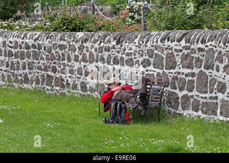 Man wearing straw  hat, laid on bench, resting. Stock Photo