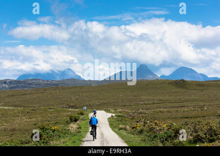 Tourists cycling by Stac Pollaidh - Stack Polly - (centre) in glacier mountain range in the North West Highlands Geopark in Coig Stock Photo