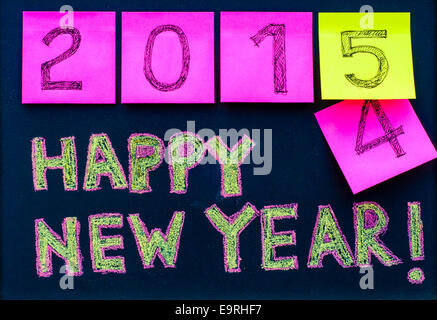 Happy New Year 2015 message hand written on blackboard, numbers stated on notes, 2015 replacing 2014 Stock Photo