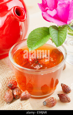 rose hips tea, red teapot and rose-hip flowers