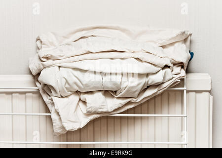 White cotton bed sheets folded on a home radiator Stock Photo