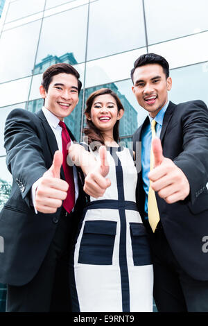 Asian business woman and men outside in front of building Stock Photo