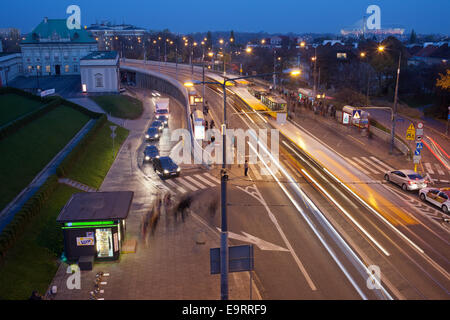 Night traffic on Solidarity Avenue (Polish: Aleja Solidarnosci), people waiting at bus and tram stops at the Old Town in Warsaw, Stock Photo
