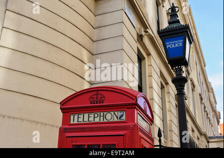 A traditional British red telephone box by an old Police lamppost in the City of London, England, United Kingdom. Stock Photo