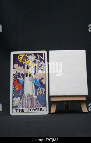 The Tower tarot card next to a blank canvas on a dark background. Stock Photo