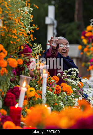 Oct. 31, 2014 - Oaxaca, Oaxaca, Mexico - An elderly woman toasts her deceased husband with a shot of mescal at Xoxocatian cemetery decorated with flowers and candles for the Day of the Dead Festival known in spanish as Dâ€™a de Muertos on October 31, 2014 in Oaxaca, Mexico. (Credit Image: © Richard Ellis/ZUMA Wire) Stock Photo