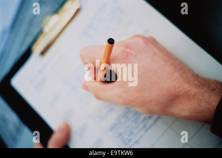 Person Writing on Clipboard Stock Photo