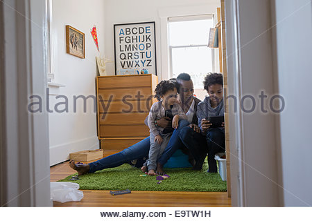 Mother and children using digital tablet in bedroom