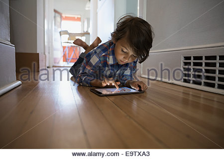 Boy using digital tablet on hallway floor