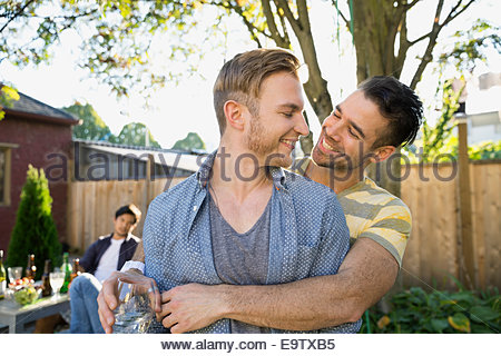 Homosexual couple hugging at backyard barbecue