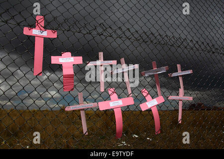 EL ALTO, BOLIVIA, 2nd November 2014. Crosses with the names of women against dark skies on a wire mesh fence, part of a memorial for recent victims of femicide and domestic violence against women. According to a WHO report in January 2013 Bolivia is the country with the highest rate of violence against women in Latin America. Credit:  James Brunker / Alamy Live News
