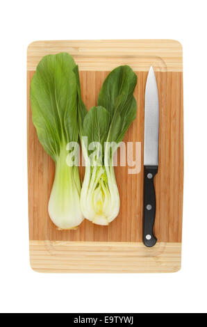 Cut Pak choi with a knife on a bamboo board isolated against white Stock Photo