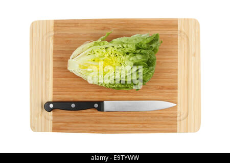 Little gem lettuce cut in half with a knife on a bamboo board isolated against white Stock Photo