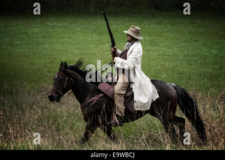 cowboy riding countryside country western old west man male rider horse rifle gun retro vintage past history historical field ho Stock Photo