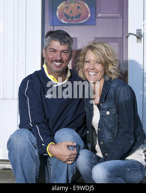 A man and woman are sitting on a step outside in front of a door. Stock Photo