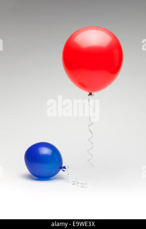 A red republican balloon floating over a partially deflated  blue democratic balloon. Stock Photo