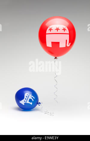 A red republican balloon floating over a partially deflated  blue democratic balloon. Stock Photo