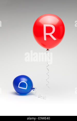 A red republican balloon floating over a partially deflated blue democratic balloon. Stock Photo