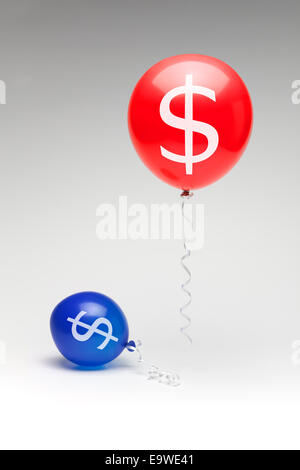 A red republican balloon floating over a partially deflated  blue democratic balloon with dollar signs. Stock Photo