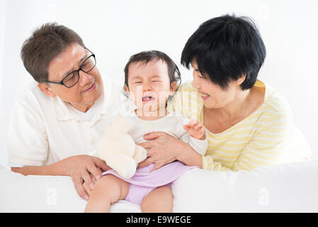 Asian family pamper crying baby girl, grandparents and grandchild indoor living lifestyle at home. Stock Photo