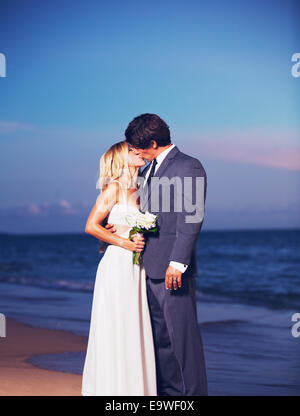 Beautiful Wedding Couple, Bride and Groom Kissing on the Beach at Sunset Stock Photo