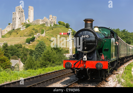 Heritage Swanage Railway with steam engine train 6695  (GWR 0-6-2T  5600 Class) in front of the historic ruins of Corfe Castle. Stock Photo