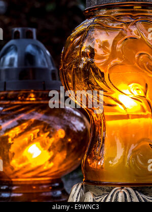 Votive candles lit on tombstone Stock Photo