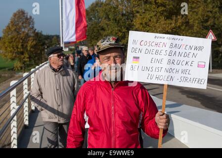 Guenter Fromm from Eisenhuettenstadt protests at the opening celebrations of the new bridge between Germany and Poland over the Neisse River in Coschen, Germany, 03 November 2014. His sign, which reads, 'In Coschen we built a bridge for the gang of thieves.' refers to the crime rate in the German border region. Seventy years later there is finally another bridge over the Neisse, connecting Coschen with Poland. The original bridge was destroyed in the Second World War. The basis for the construction comes from a government agreement between Germany and Poland. From the total costs of 5.4 mil Stock Photo