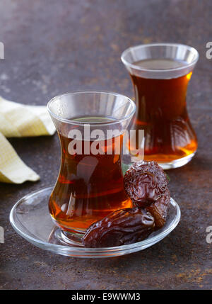 Turkish tea in traditional glass with sweet dates Stock Photo