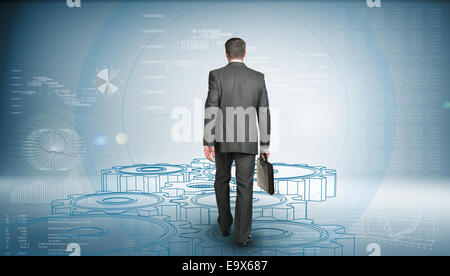 Businessman in suit holding briefcase and goes forward. Rear view. Wire-frame gears gear underfoot Stock Photo