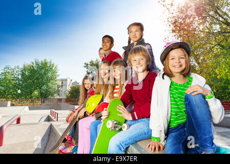 Many children with skateboards and helmets sitting Stock Photo