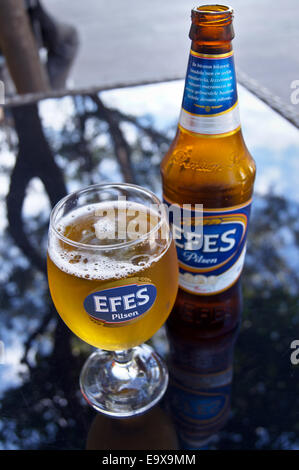 A glass and bottle of Efes Turkish beer,  Bodrum, Turkey, pub table drinks glasses Stock Photo