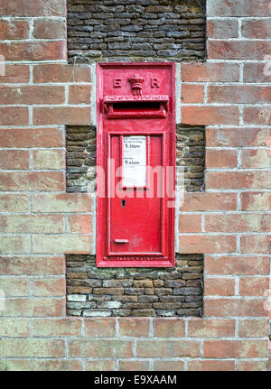 Red post box put into the wall around Sandringham House during the reign of king Edward VII, the first british monarch to own it Stock Photo