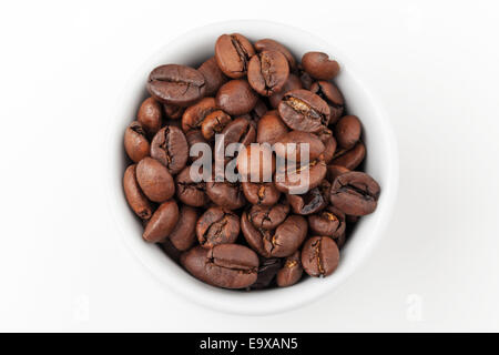 Small white espresso cup full of fresh roasted coffee beans on white background, top view Stock Photo