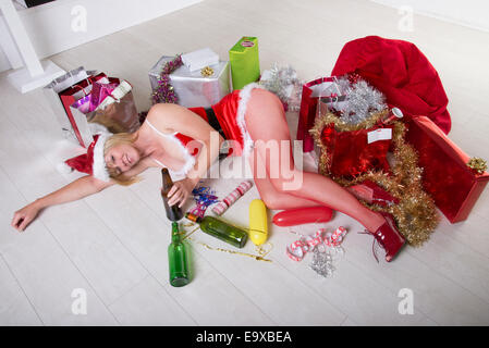 Female party goer on the floor wearing a fancy dress Santa outfit and drinking alcohol Stock Photo