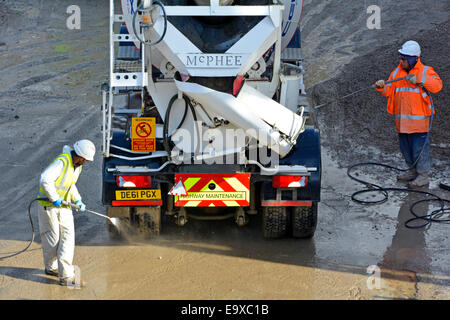 Ready mix concrete cement mixer truck reversing towards public highway removing dirt pressure washed off wheels in Southwark South London England UK Stock Photo