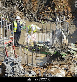 Cutting back & cleaning up concrete pile tops to prepare for foundations in wet muddy basement excavations Southwark South London England UK Stock Photo