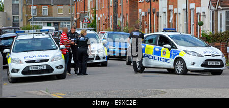 Street scene in residential road three Essex police cars and officers attending incident & policeman interviewing witness Brentwood Essex England UK Stock Photo