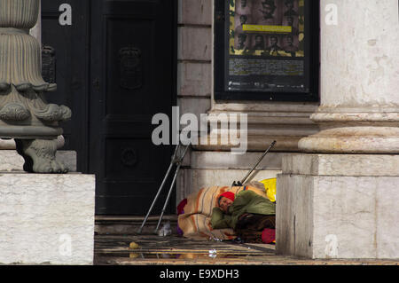 Horizontal portrait of a rough sleeper laying in the doorway of the Teatro Nacional D. Maria II in Lisbon. Stock Photo