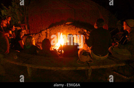 group of people sitting around campfire  playing music singing songs at Esalen Institue in Big Sur California usa Stock Photo