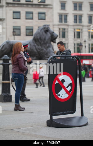 Trafalgar Square. London. England. Sign signifing no, to feeding feral pigeons (Columba livia domest). 'Landseer Lion' behind. Stock Photo