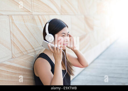 A young woman relaxing using a smartphone with headphones Stock Photo