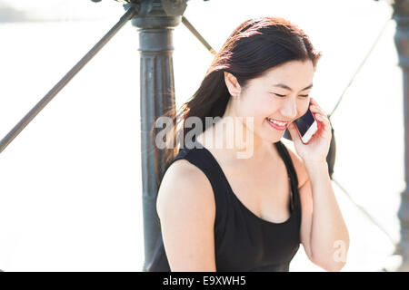 A young Asian woman talking on a smartphone outdoors Stock Photo