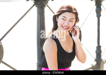 A young Asian woman talking on a smartphone outdoors Stock Photo